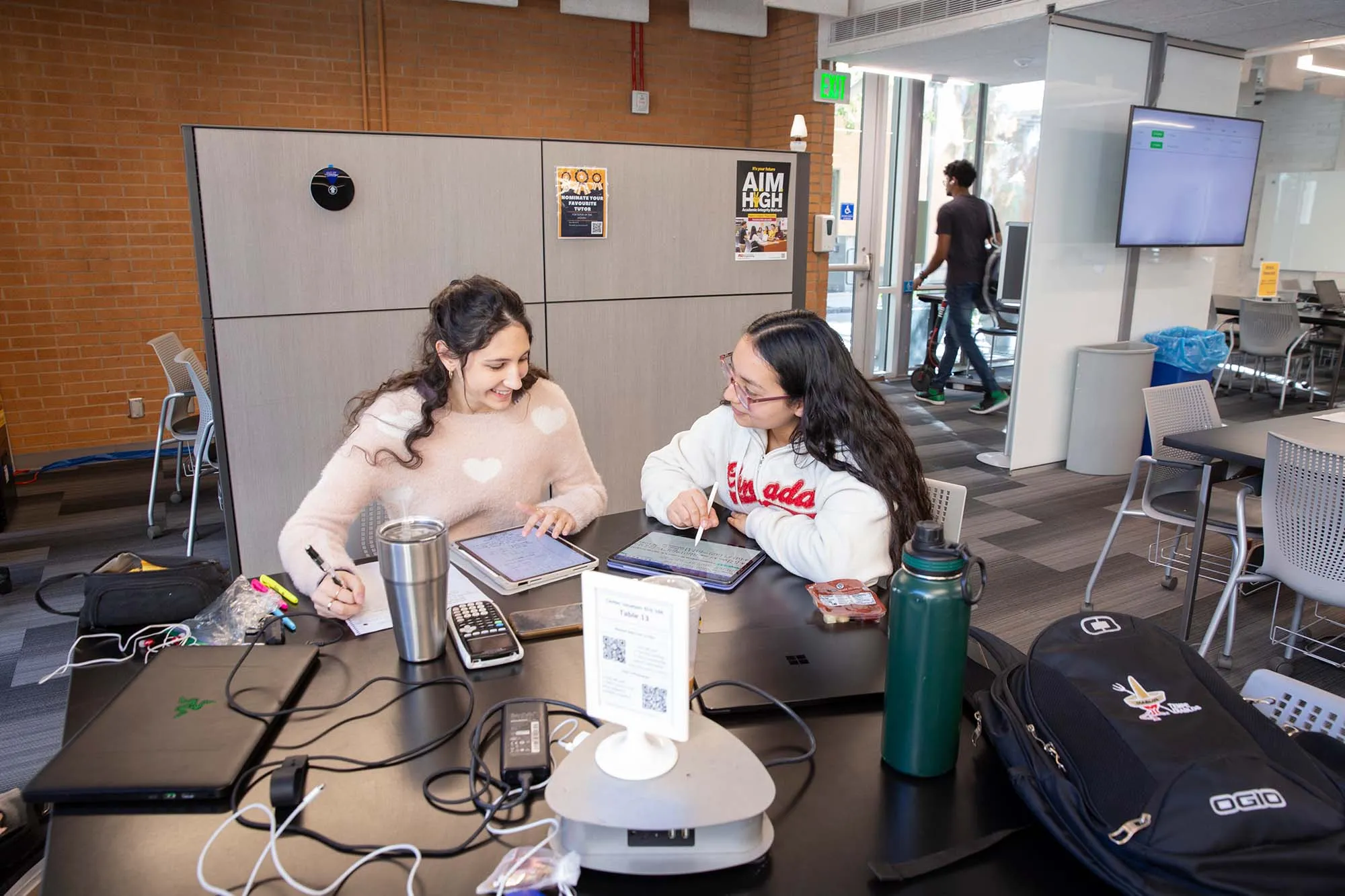 Two builders working through a problem together on campus