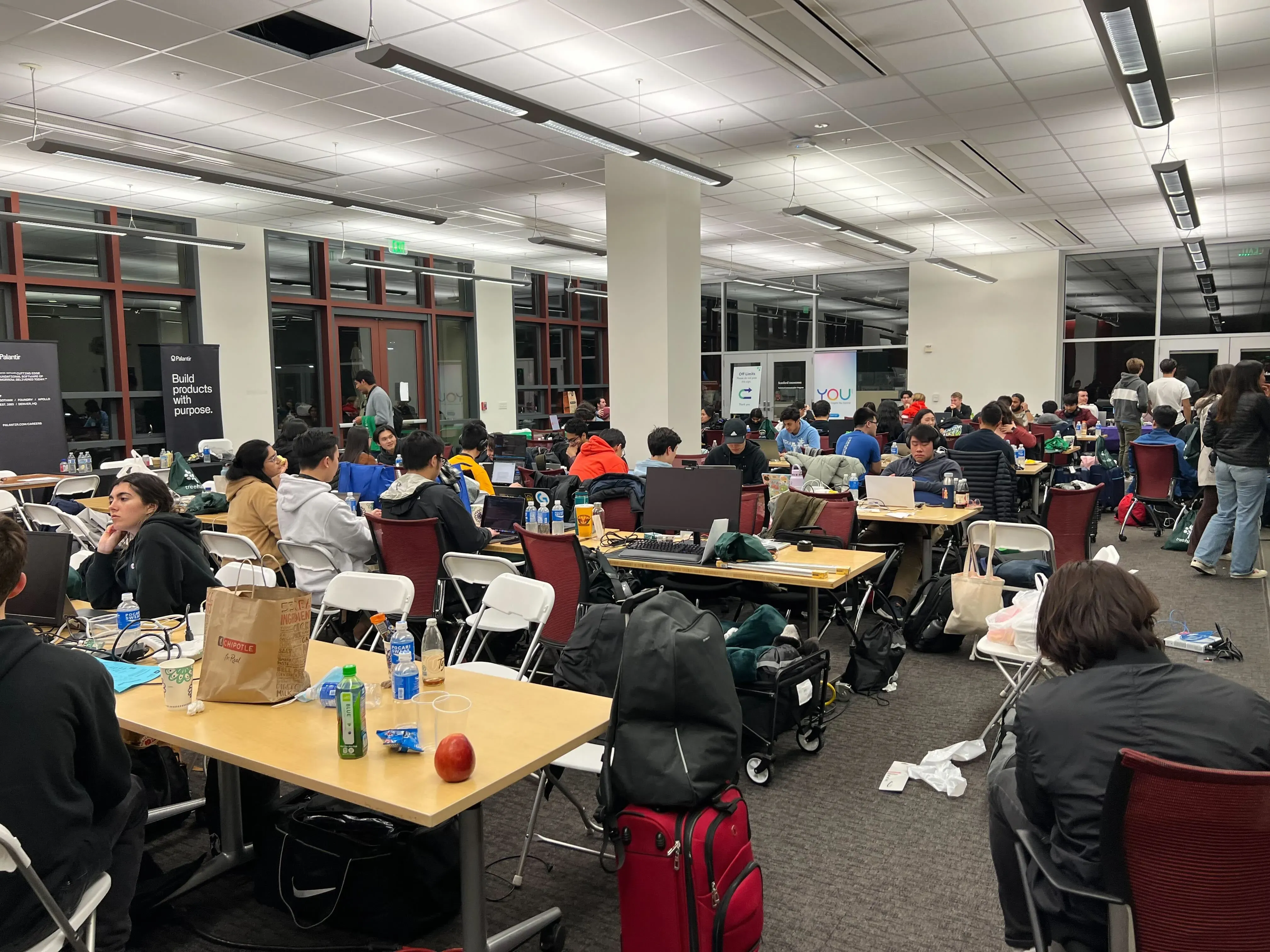 A packed hackathon floor of builders working late