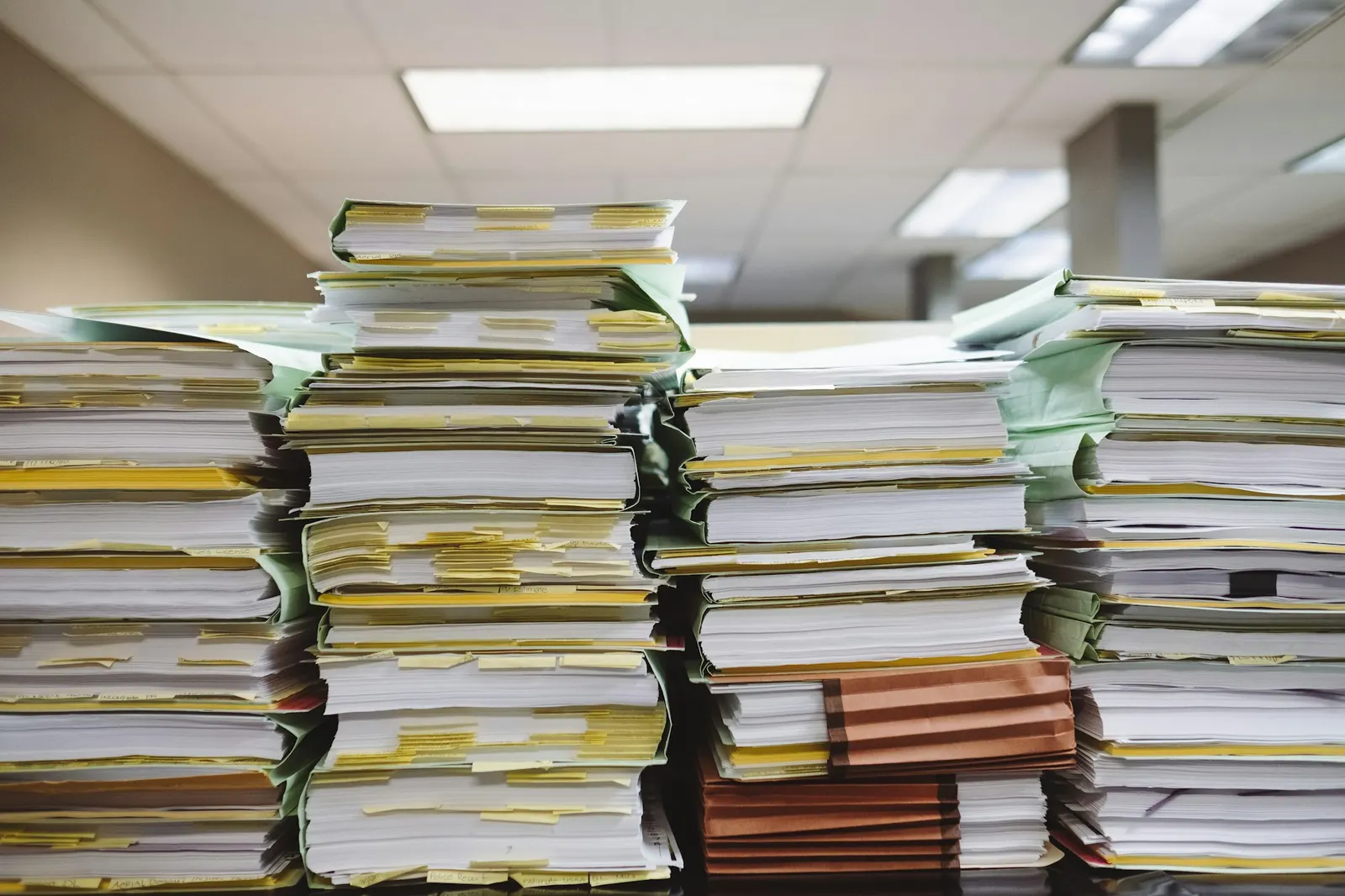 Stacks of paper documents and file folders organized on a desk
