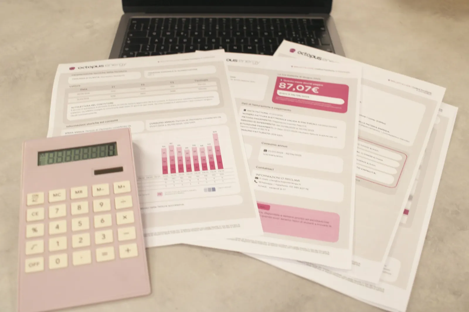 Bookkeeper working through bills with a calculator and laptop on a desk