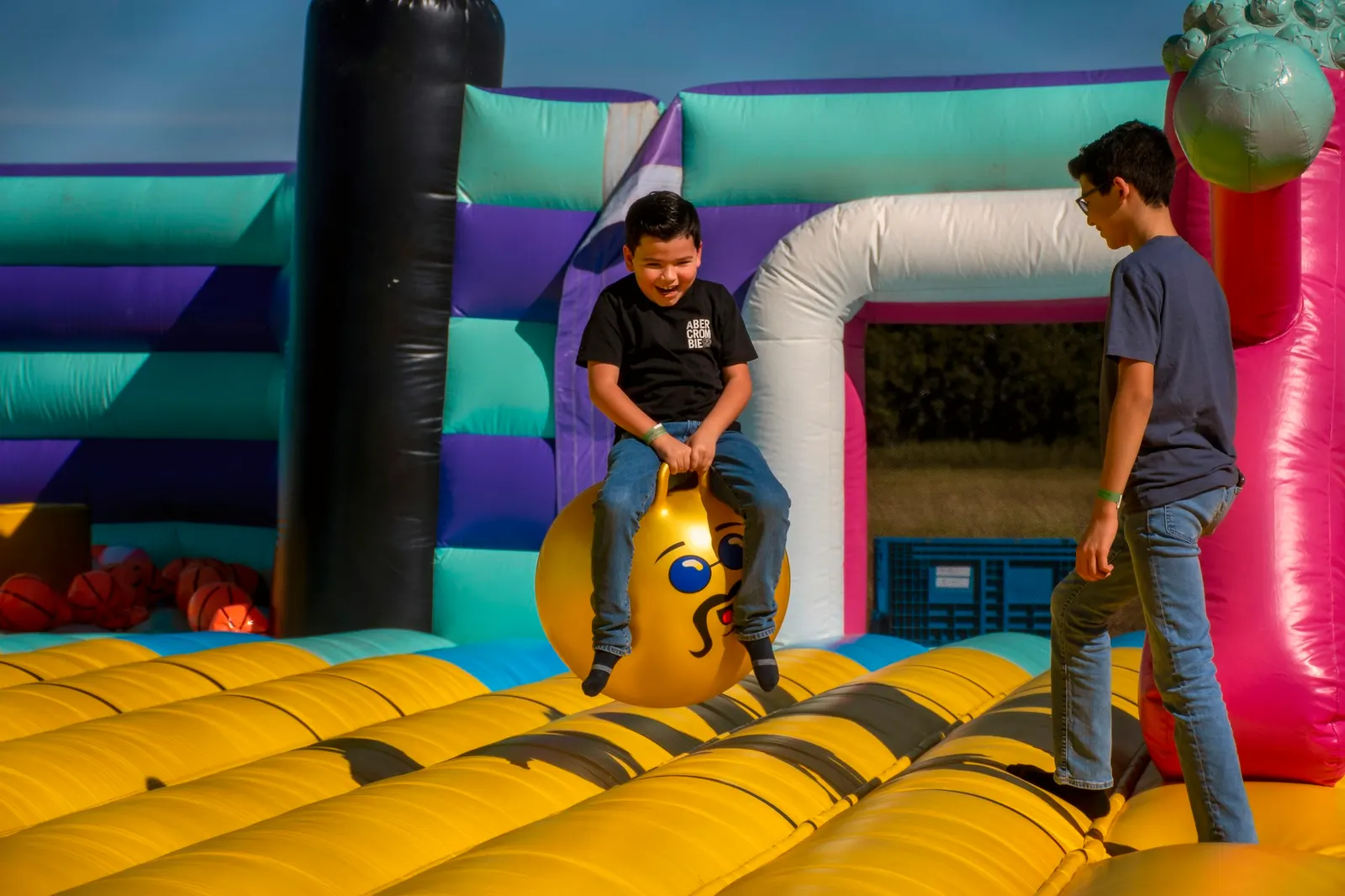 Two kids playing inside a colorful inflatable bounce castle