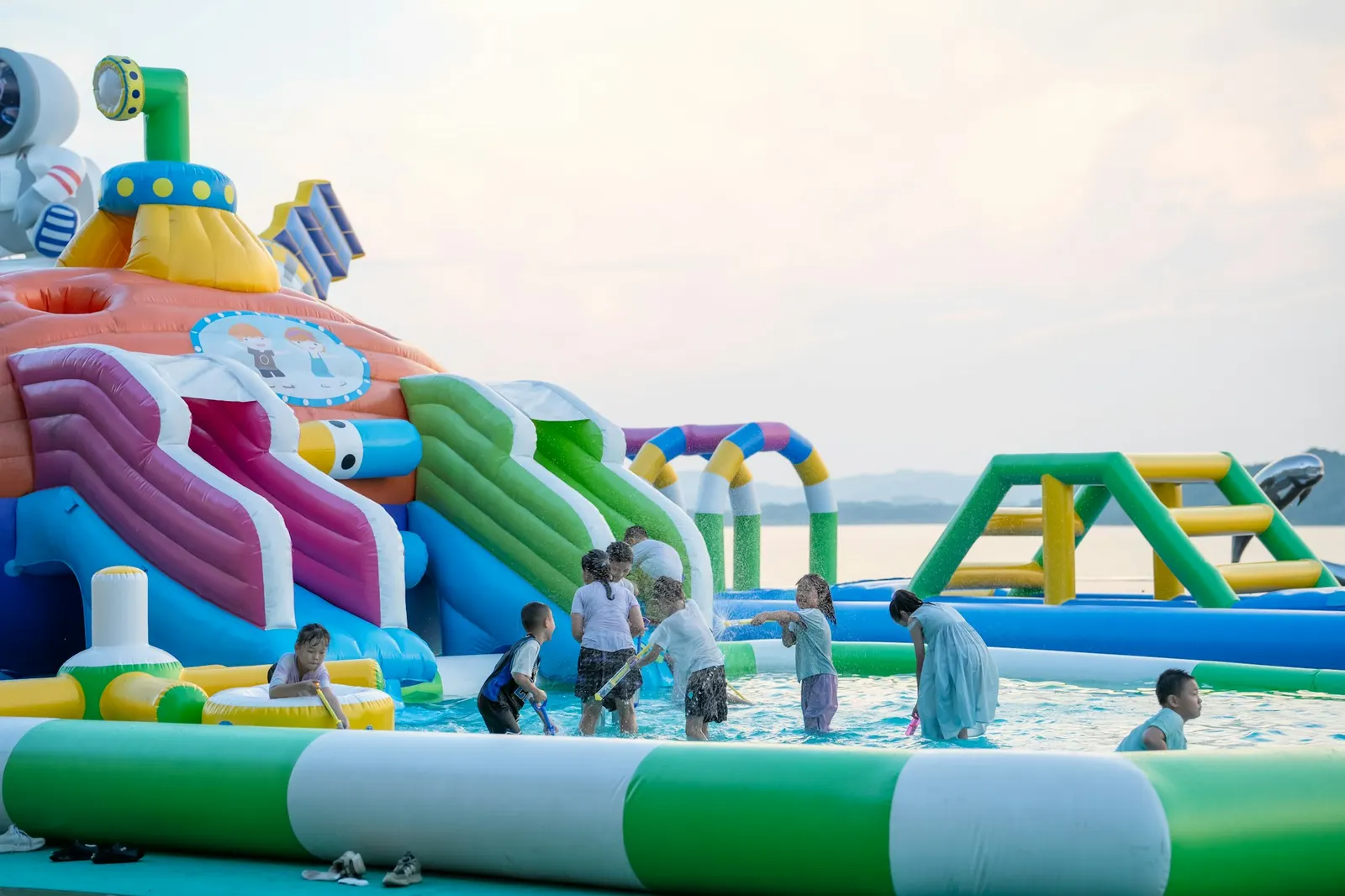Children playing on a colorful inflatable water slide park in summer