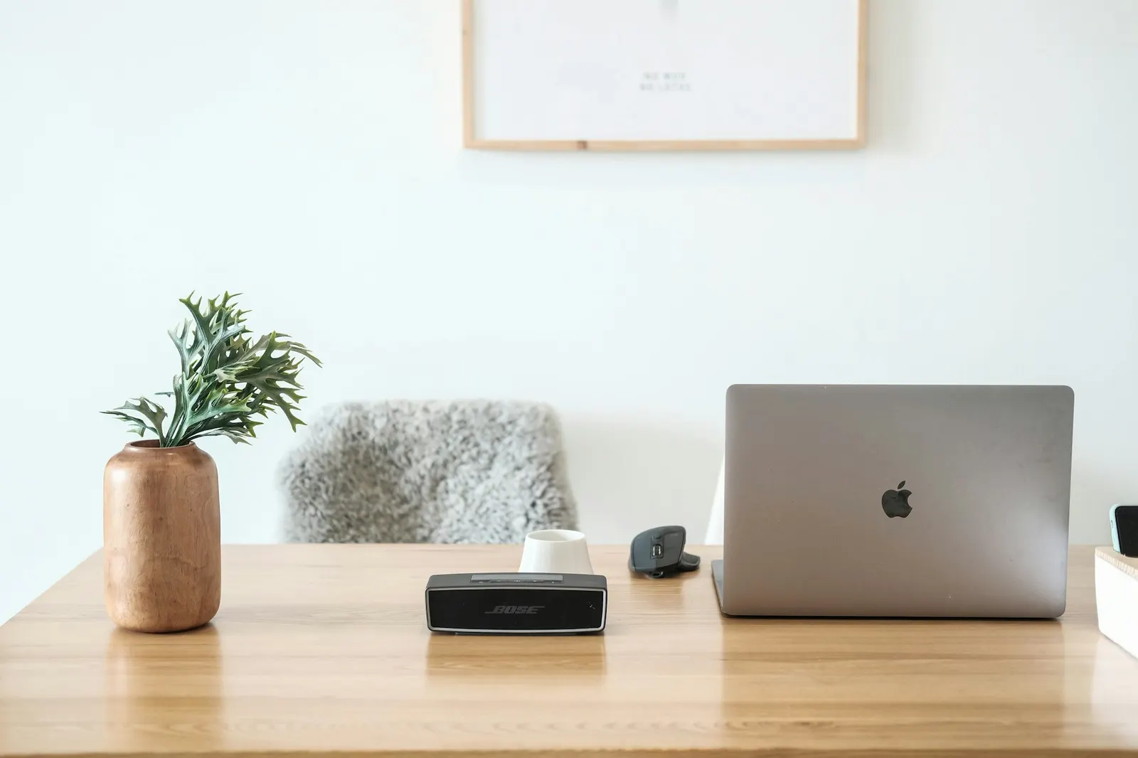 Laptop and speaker on a clean wooden desk in a bright home office