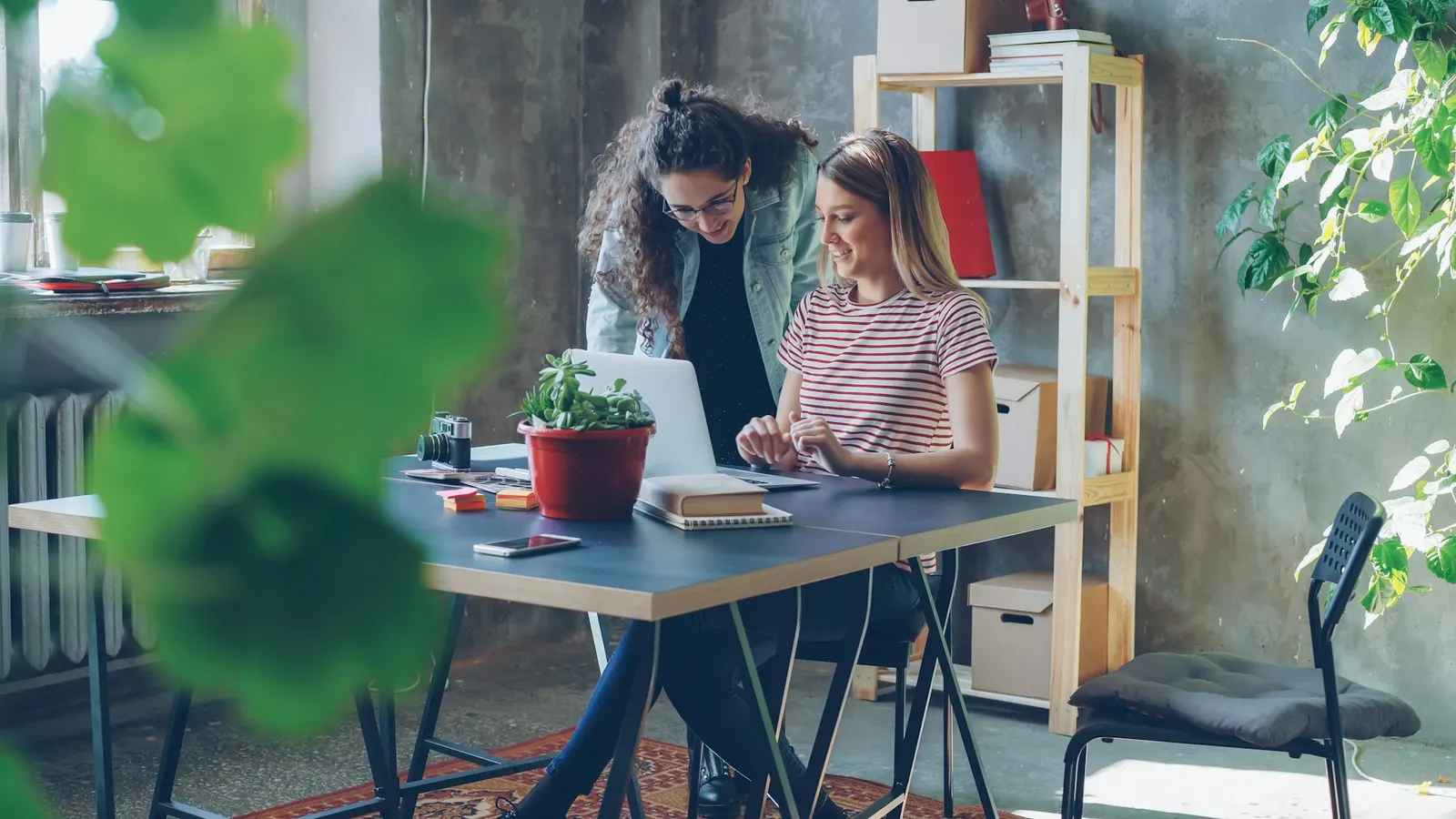 Two colleagues collaborating over a laptop in a bright office