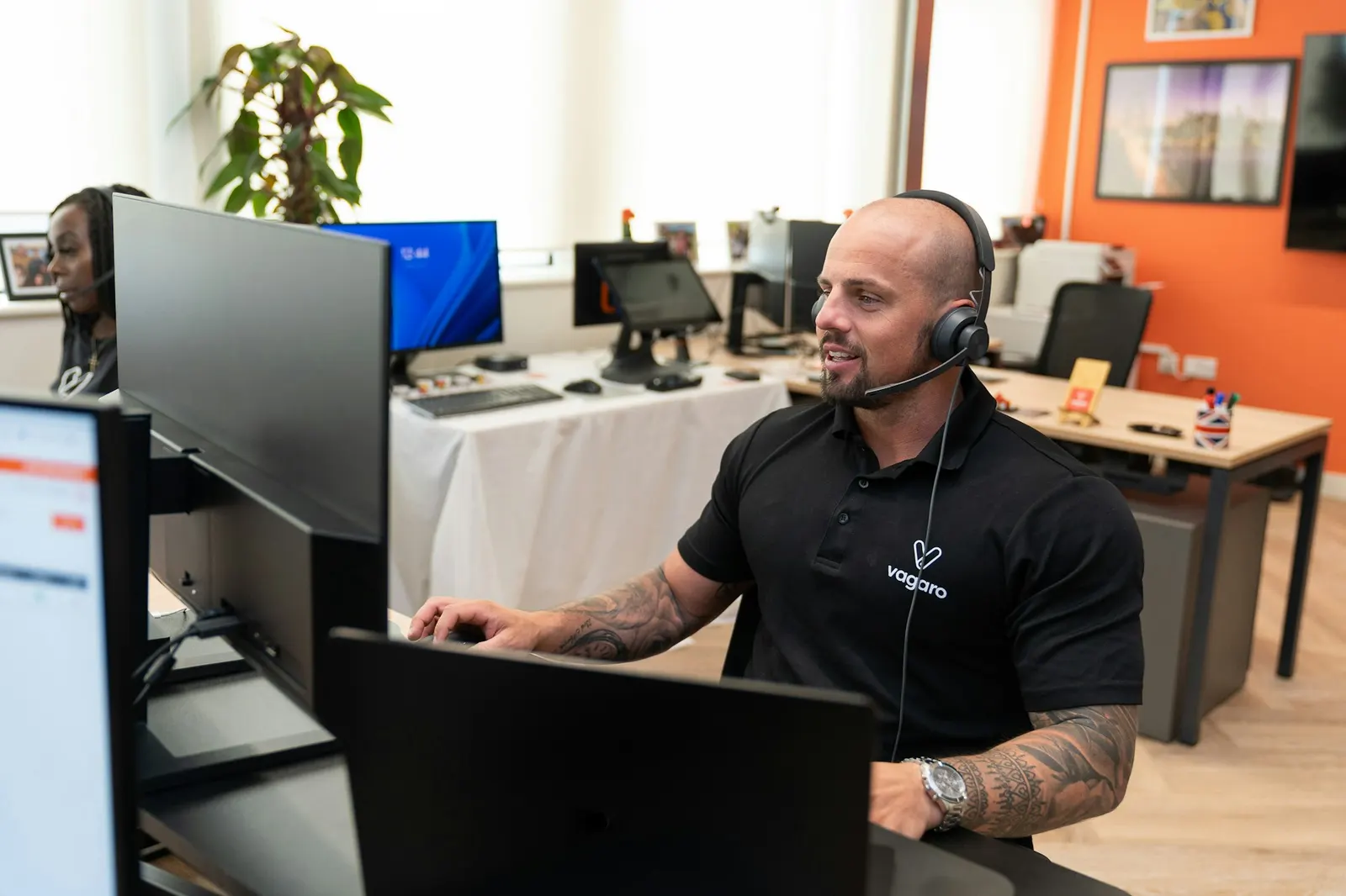 Dispatcher wearing a headset working across two monitors in a small office