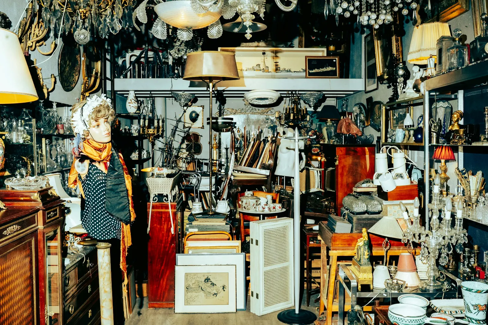 Cluttered antique shop packed with old dressers, lamps and framed pictures