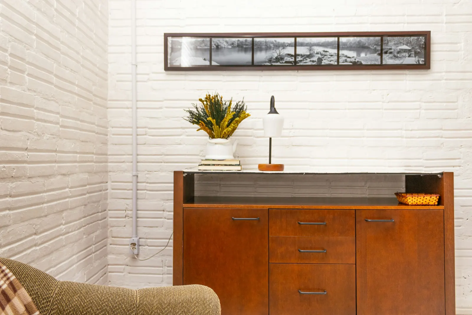 Restored mid-century teak sideboard staged with a lamp in a bright white room