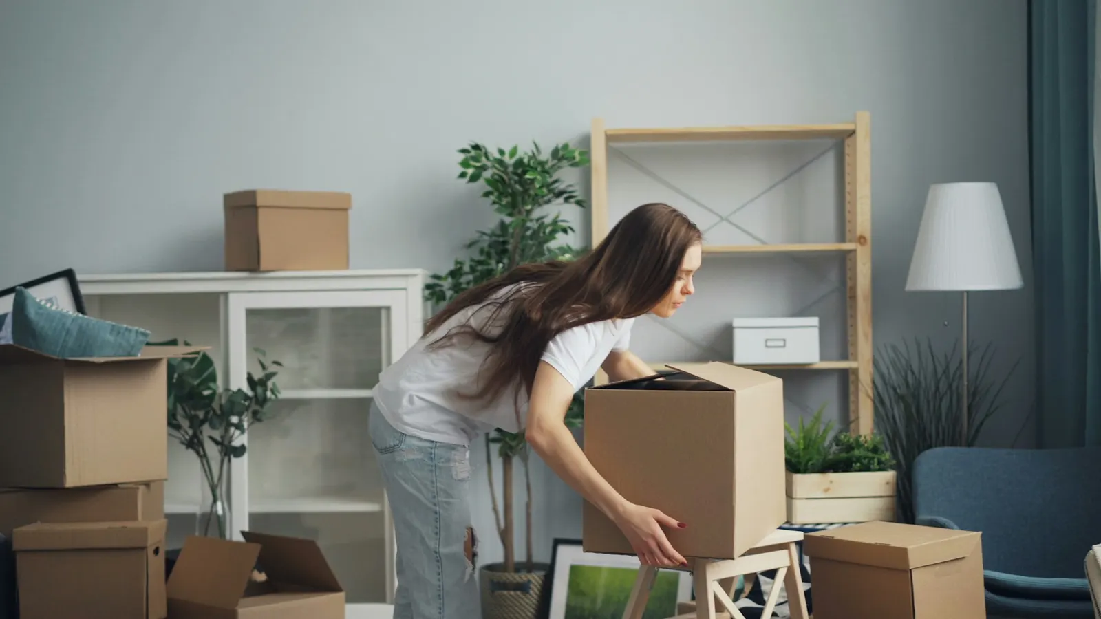 Woman sorting belongings into cardboard boxes in a bright living room
