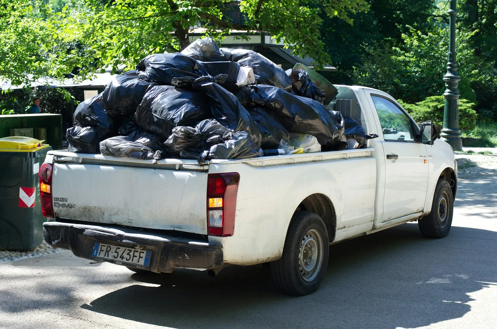 White pickup truck bed piled high with black trash bags and debris