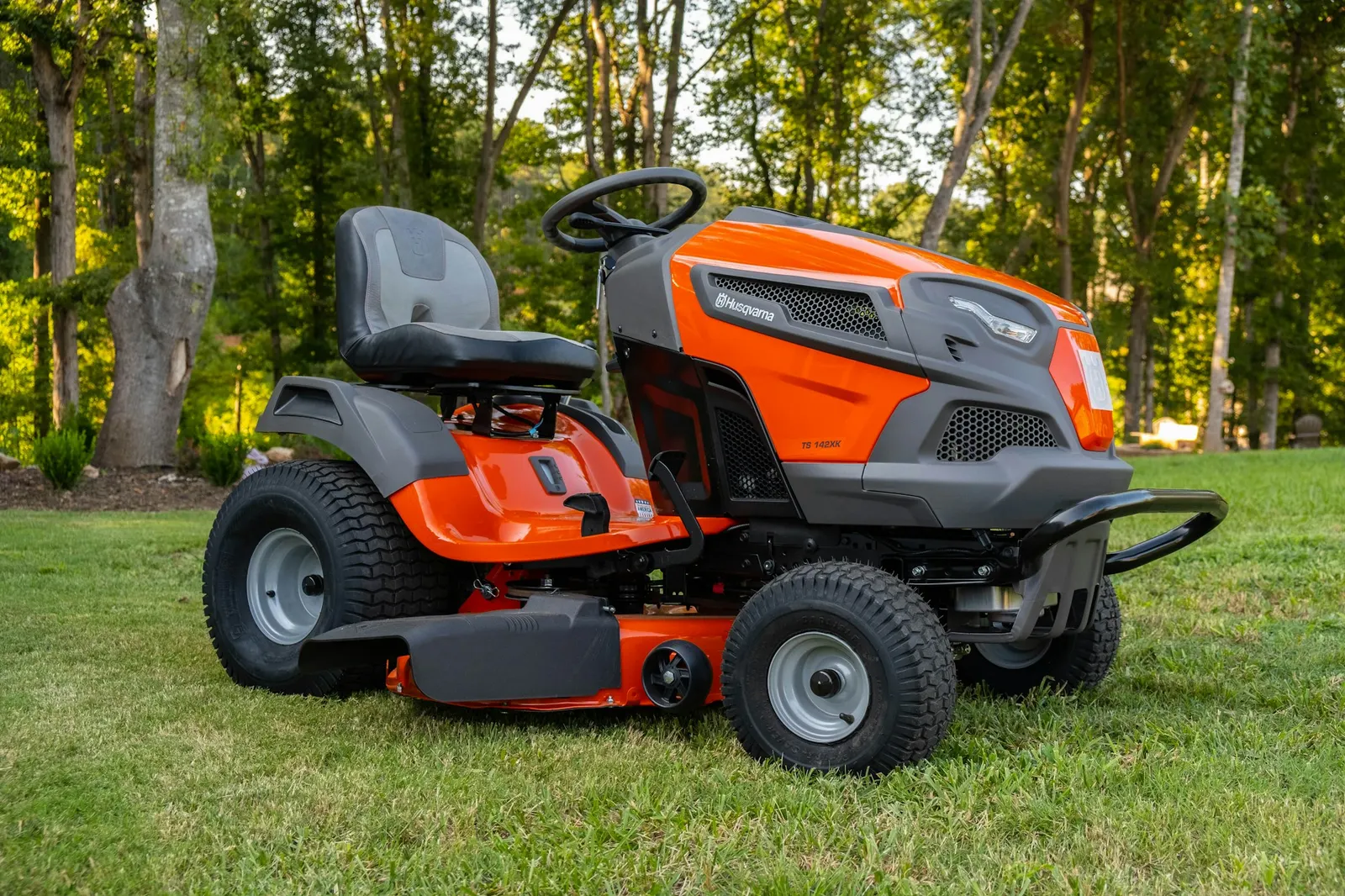 Orange riding lawn mower parked on freshly cut green grass