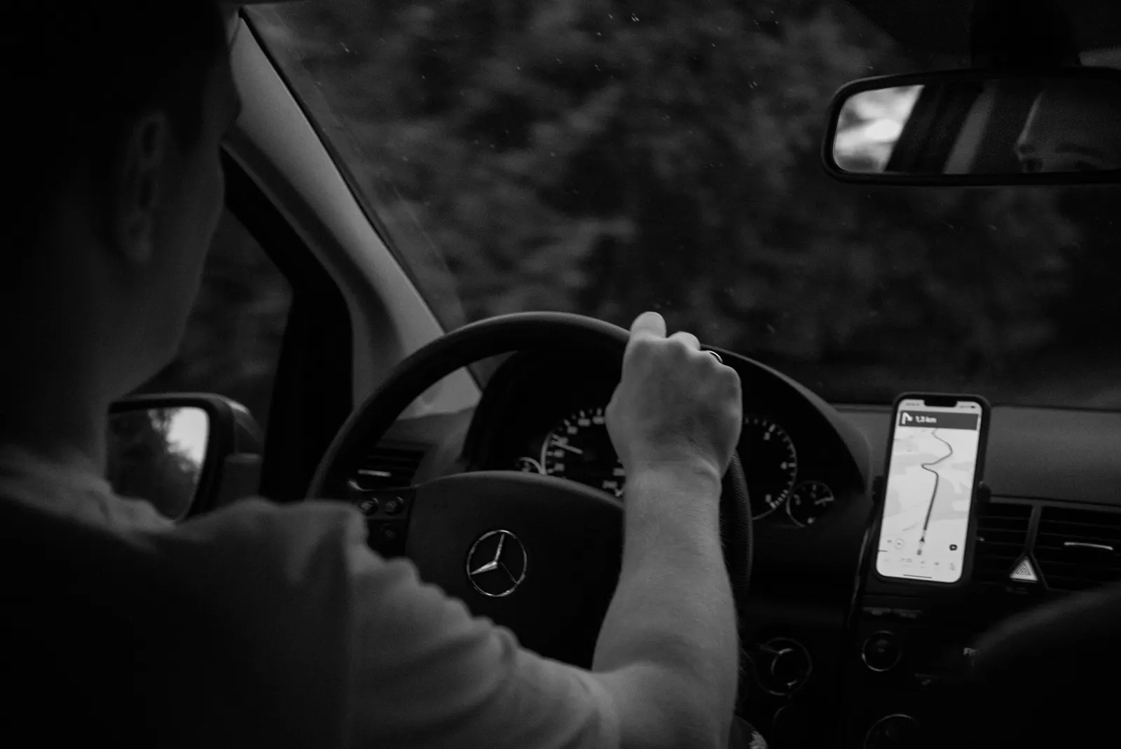 Driver behind the wheel checking GPS navigation on a phone mounted in the car