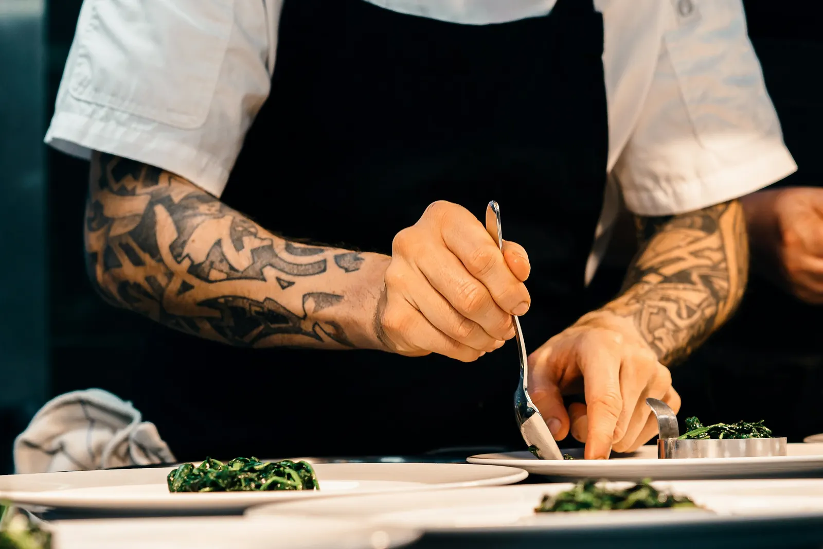 Chef carefully plating a dish and finishing it with fresh green garnish