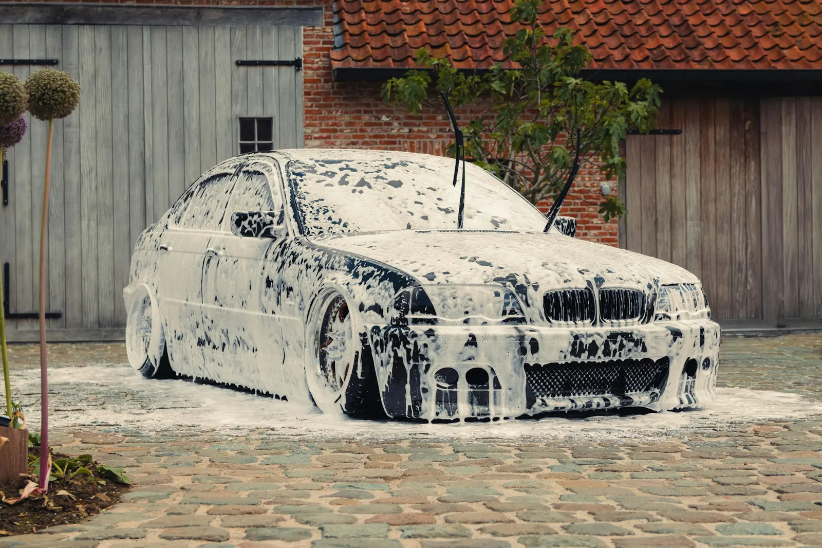 Car completely covered in thick white snow foam during a wash