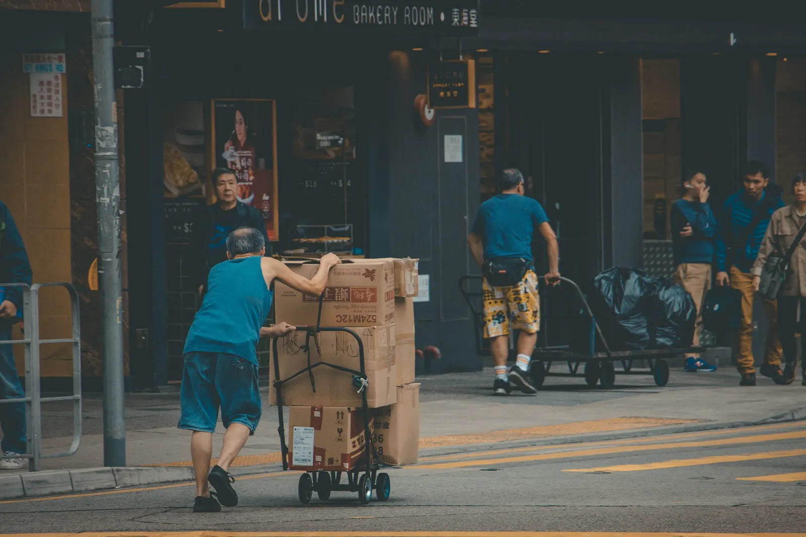 Mover pushing a hand truck loaded with cardboard boxes across a street
