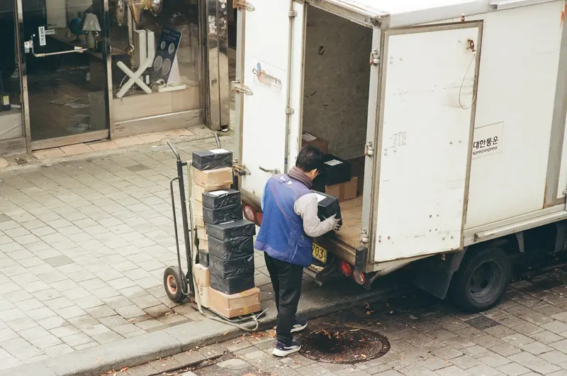 Mover unloading stacked boxes from a box truck onto a hand dolly