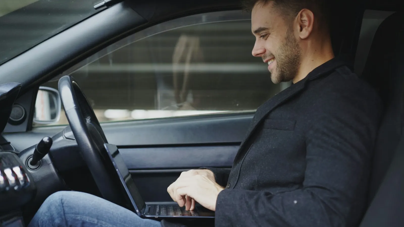 Driver reviewing schedules on a laptop from the front seat of a vehicle