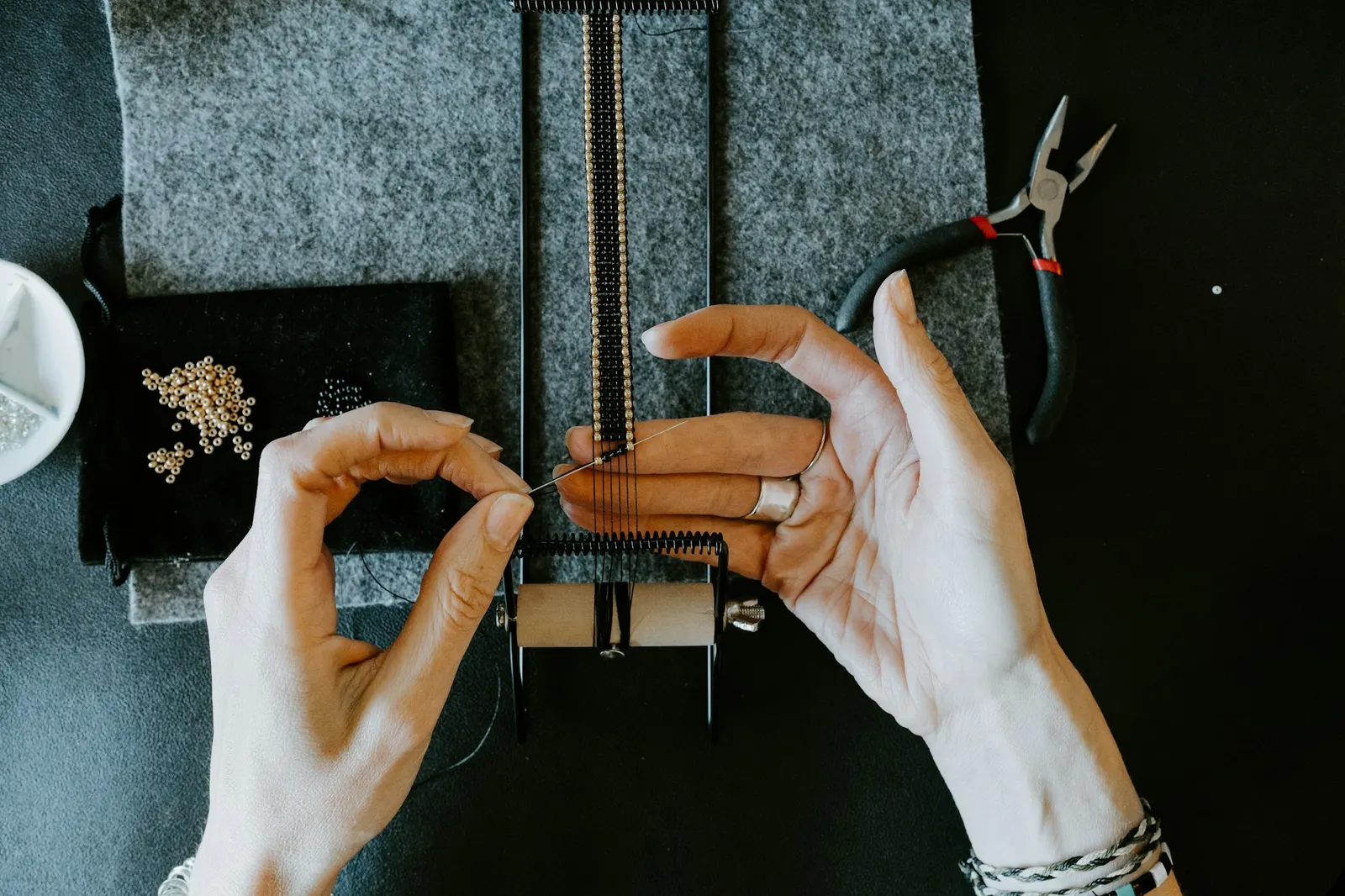 Jeweler working on a delicate chain bracelet with pliers at a workbench