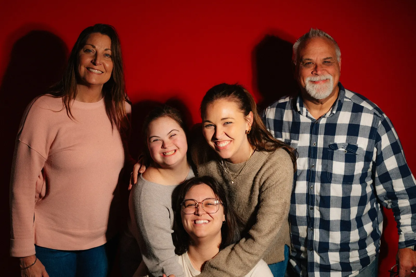 Happy family of five posing together for a portrait in a bright studio