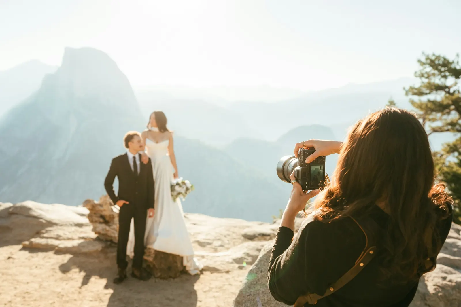 Photographer shooting a bride and groom on a mountain overlook at golden hour