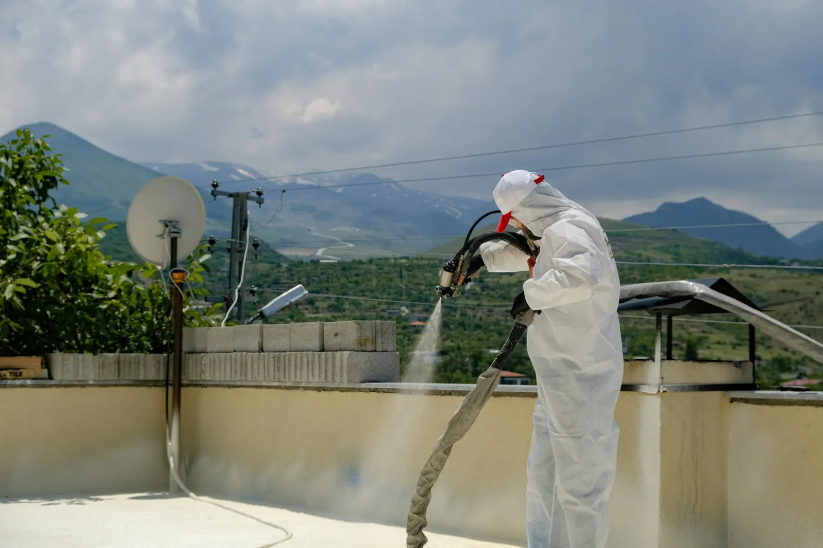 Technician in protective suit spraying down a house roof and exterior