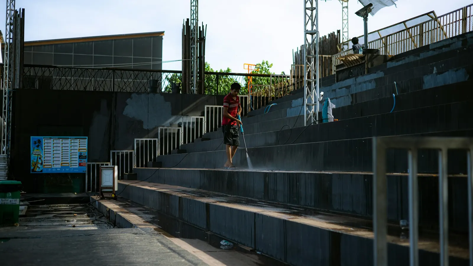 Worker pressure washing the concrete steps of a stadium seating area