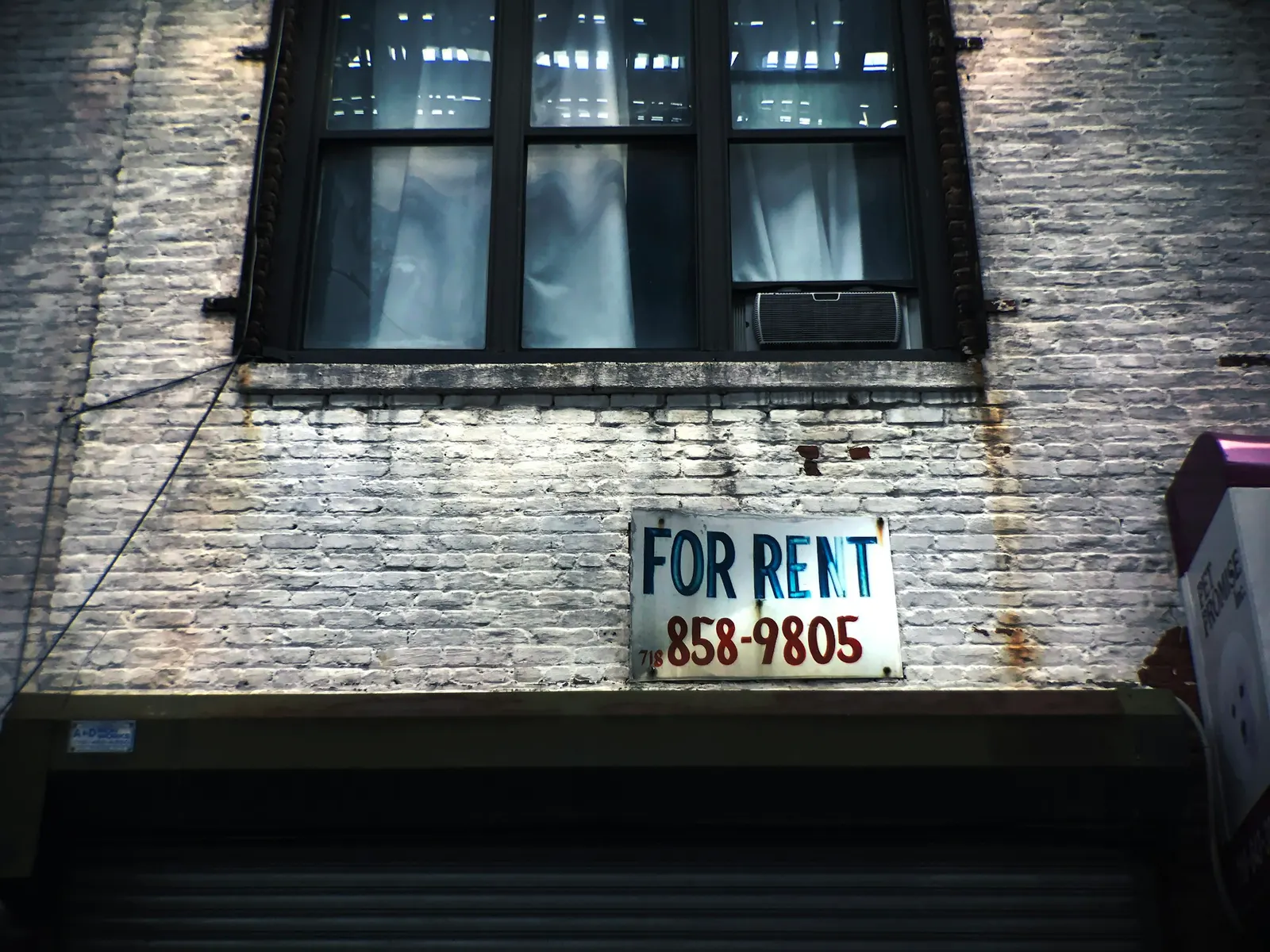 Hand-painted for rent sign on the brick wall of a city building