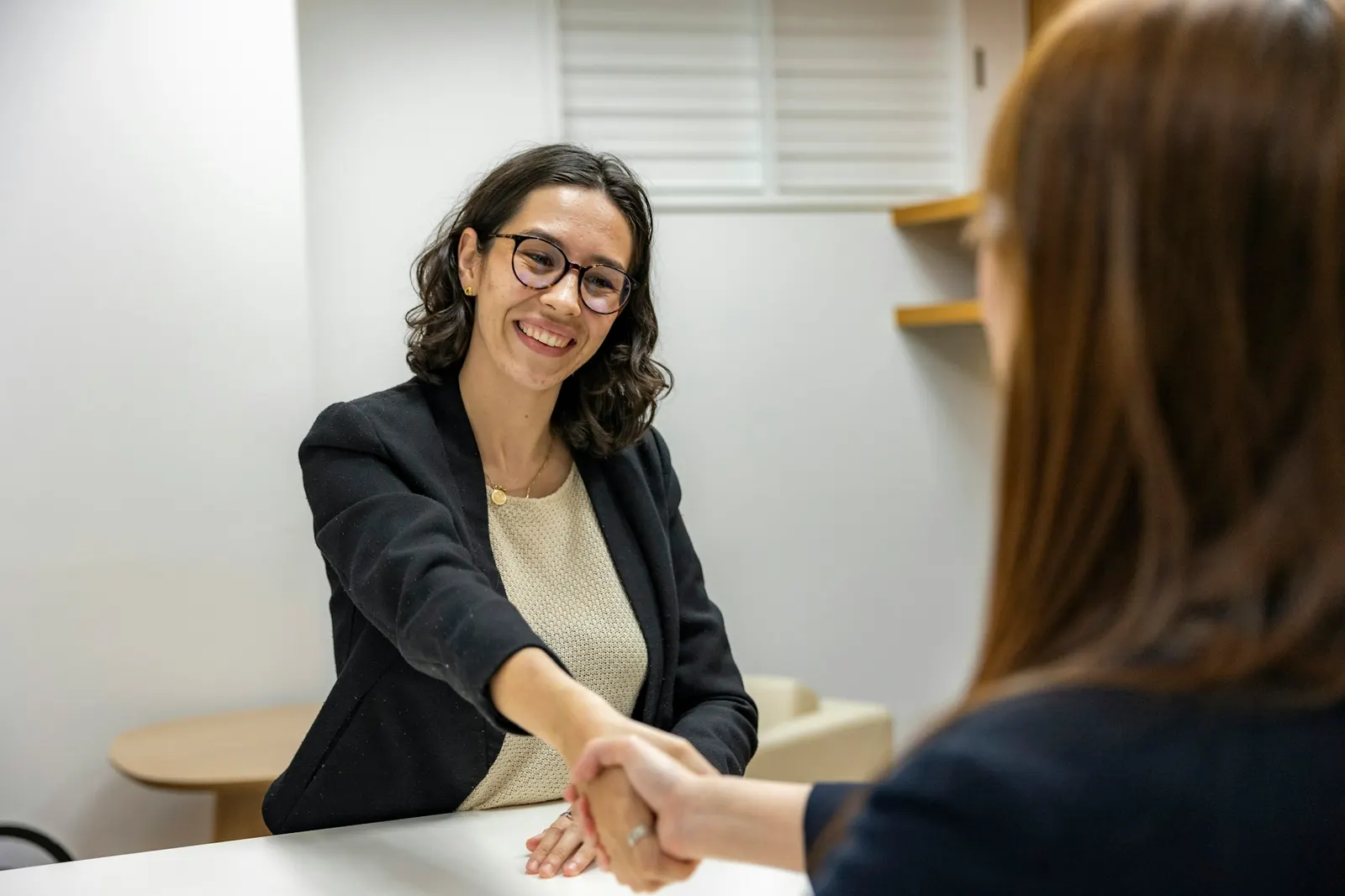 Recruiter and candidate shaking hands across the table after a job interview