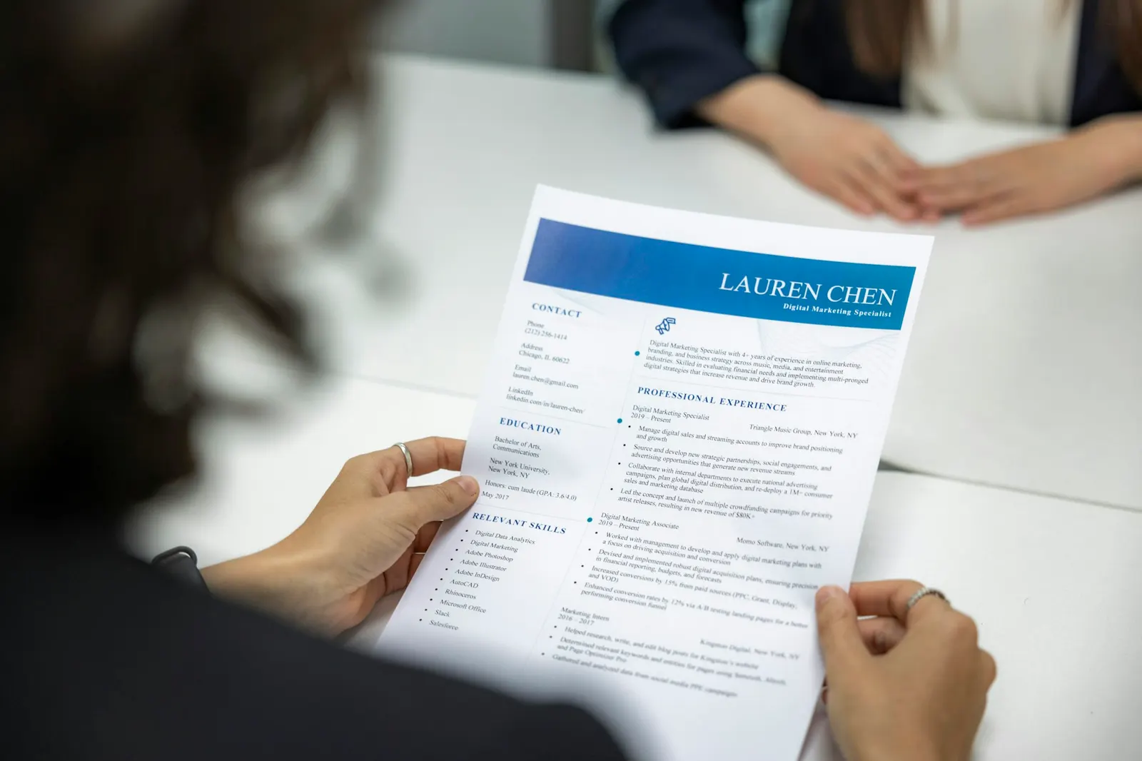 Hiring manager reading a printed candidate resume at an interview table