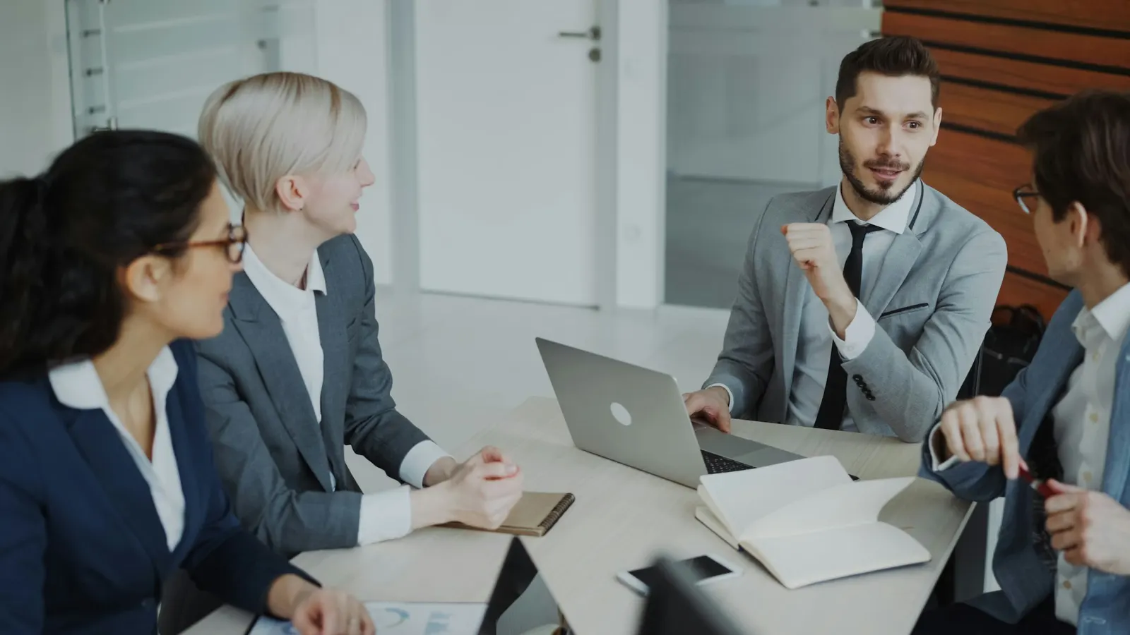 Four professionals in a team meeting around a table in a modern office