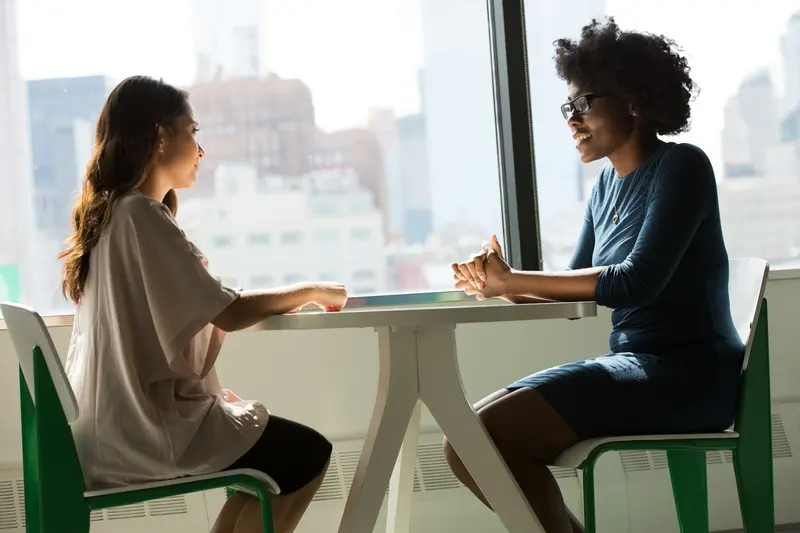 Recruiter interviewing a candidate across a table in a bright city office
