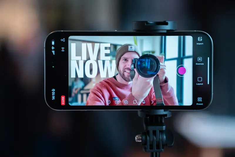Creator filming a live video of himself with a smartphone mounted on a tripod