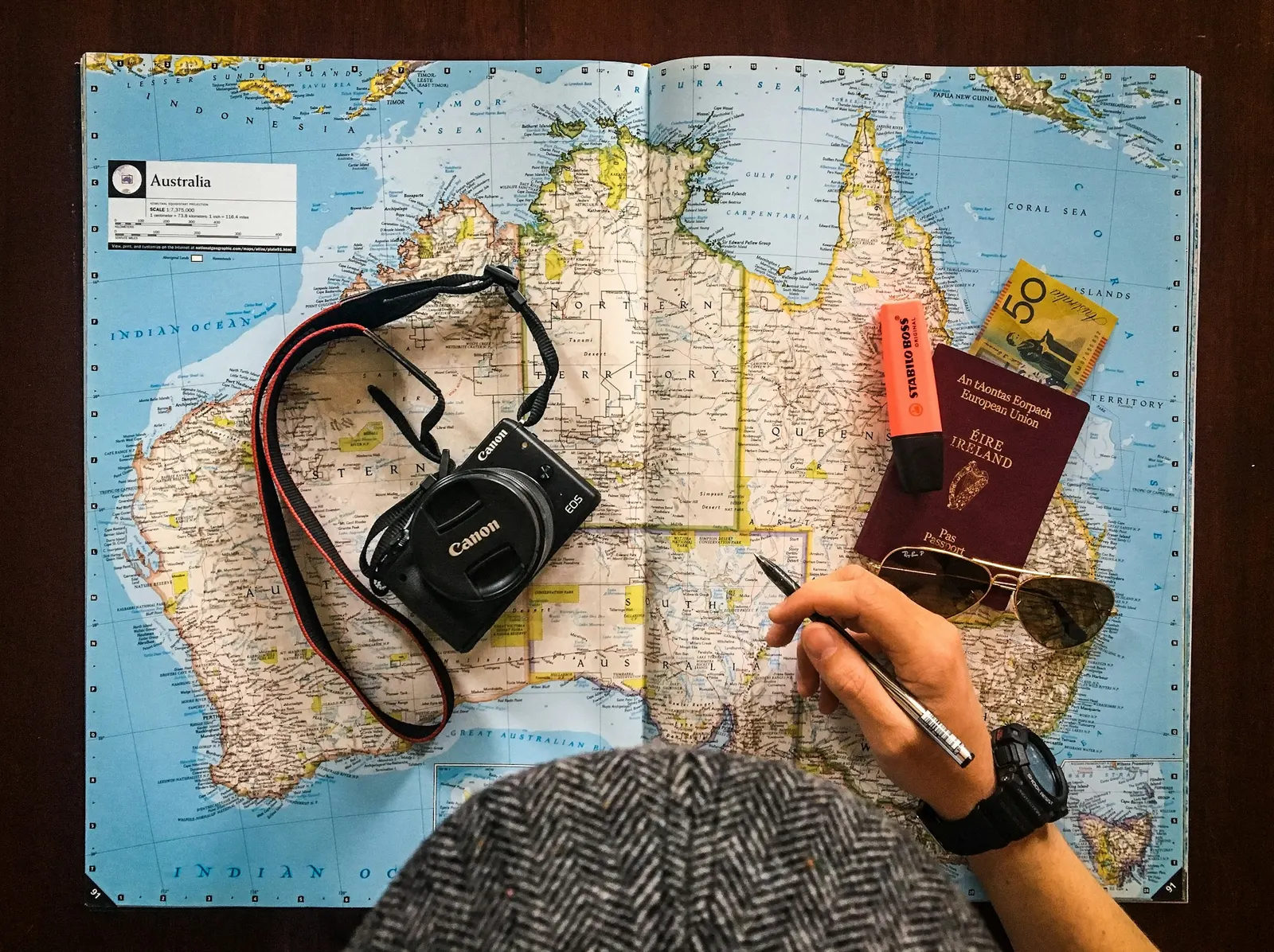 Travel planner marking a route on a world map beside a camera and passport
