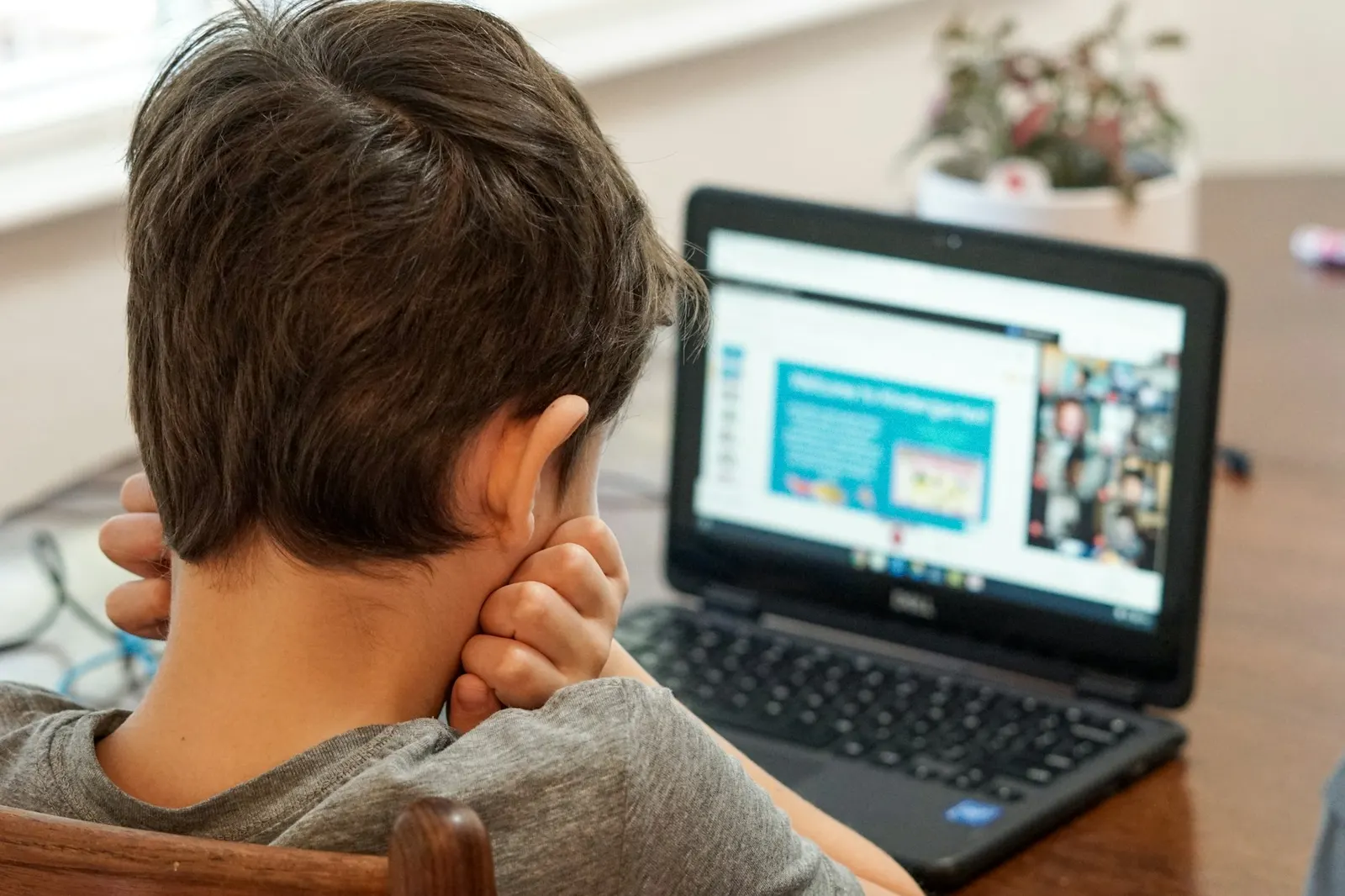 Boy at a laptop joining a live online class with the teacher on screen