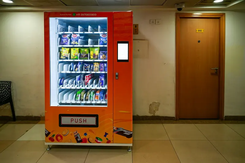 Modern snack and drink vending machine with card reader in a building corridor