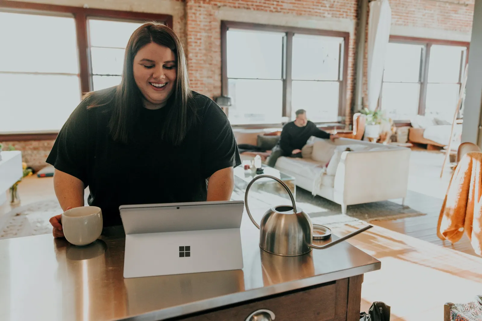 Remote worker at a kitchen table on a laptop, taking a call from home