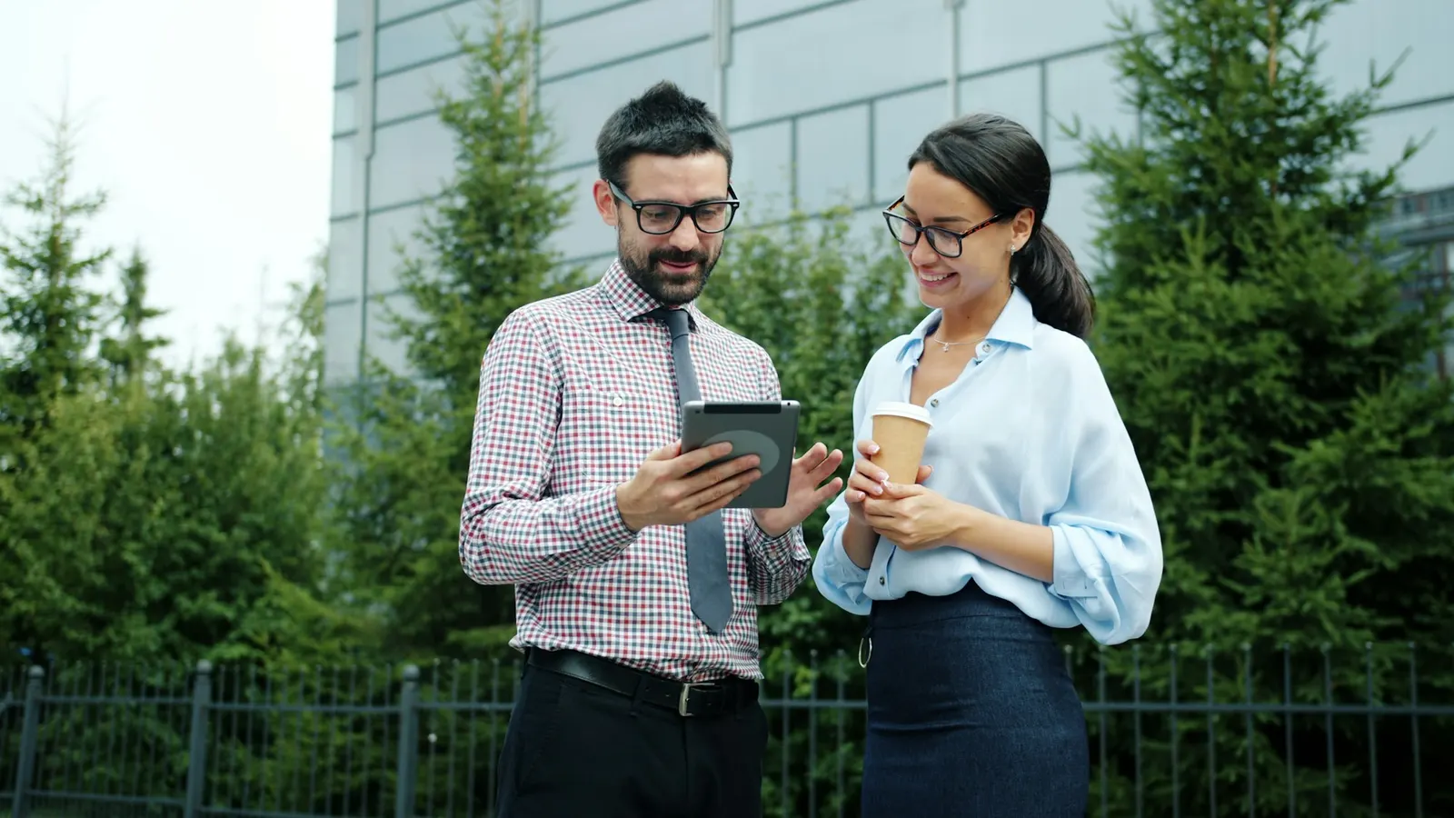Designer and client reviewing a design together on a tablet outside an office