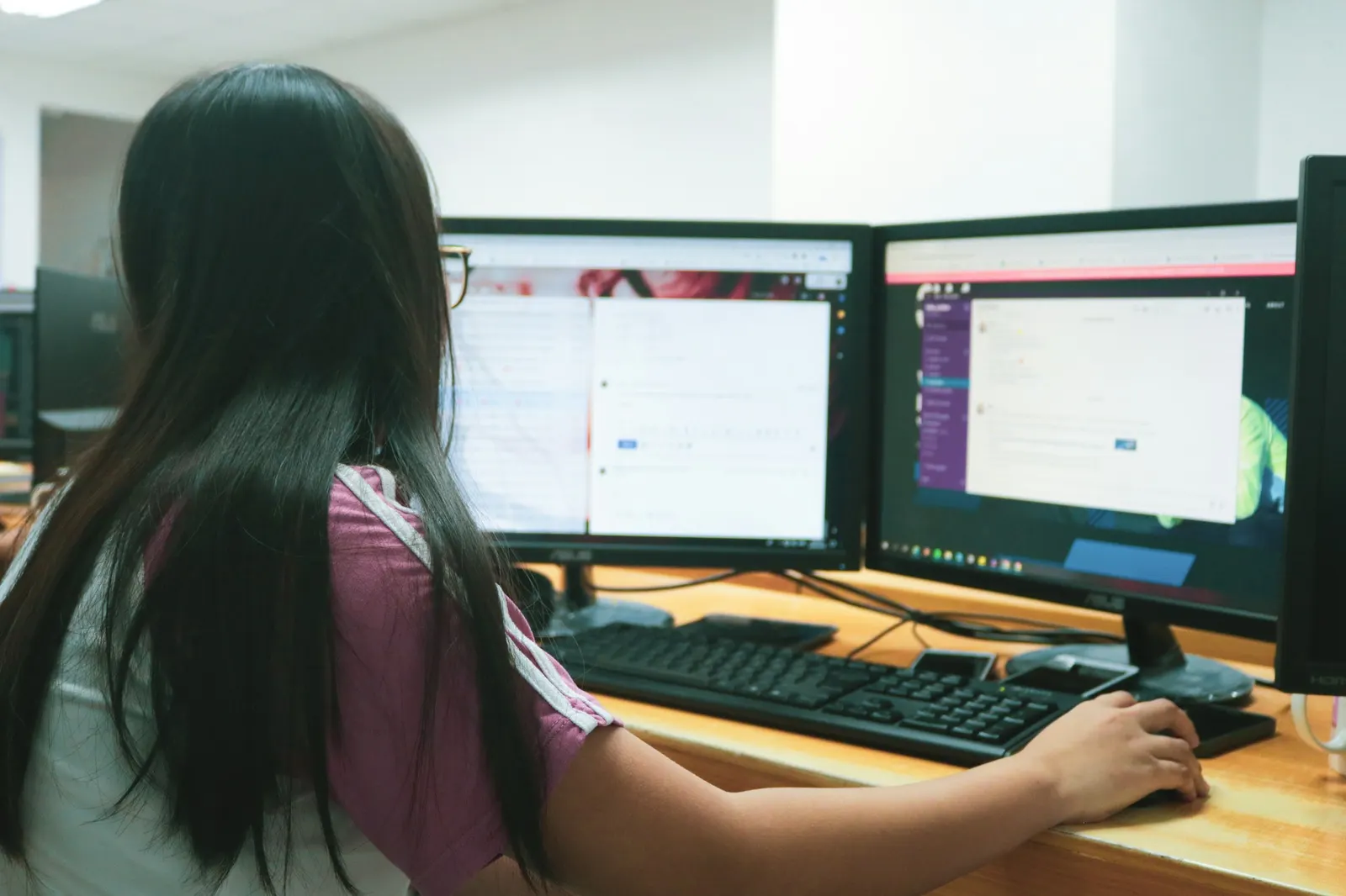 Designer working on a website layout across two large desktop monitors