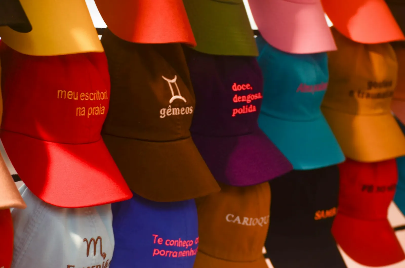 Colorful baseball caps with custom embroidered text and symbols on display