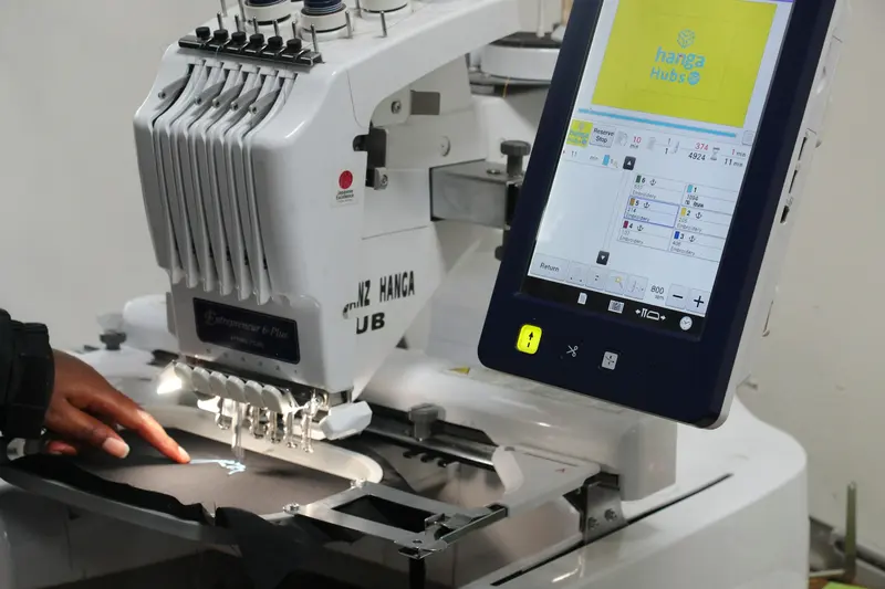 Close-up of an operator guiding fabric on a commercial embroidery machine